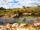 Rio do Cerrado com vegetação nativa na margem e área de pasto ao fundo