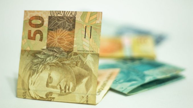 Moedas e cédulas de real sobre uma superfície