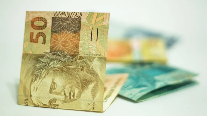 Moedas e cédulas de real sobre uma superfície