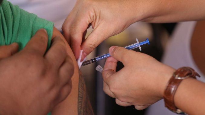 Profissional de saúde aplica vacina em paciente em posto de saúde