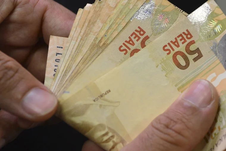 Notas e moedas de real sobre uma superfície. Foto: Agência Brasil